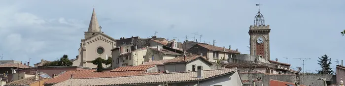 Toits du centre ancien d'Aubagne avec le clocher pointu d'une église et la tour de l'Horloge à campanile en fer forgé