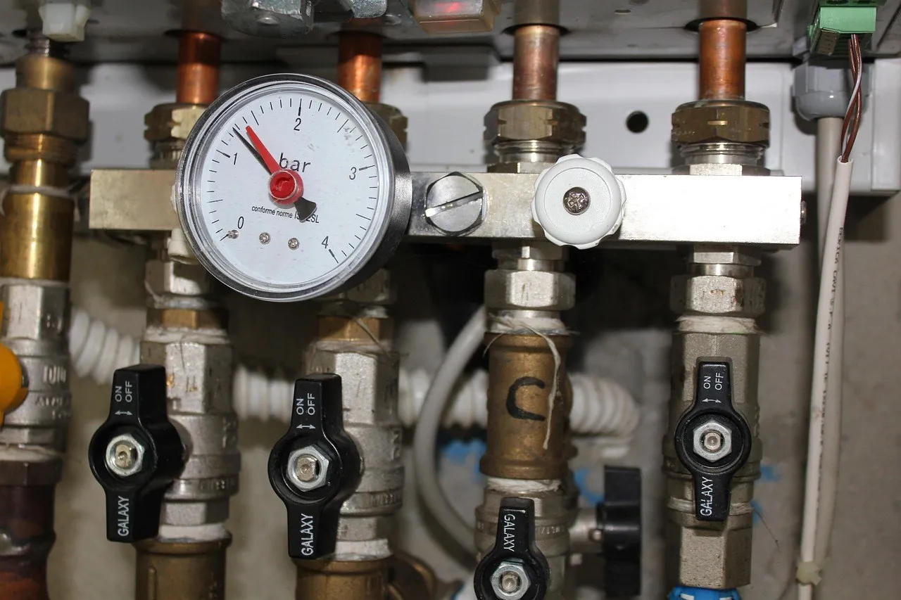 Collecteur hydraulique de chauffage avec manomètre gradué en bars et vannes à poignée noire sur tubes de cuivre