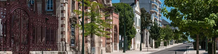 Demeure de brique et de pierre derrière une grille en fer forgé, le long de l'avenue de Champagne à Épernay, sous un ciel bleu