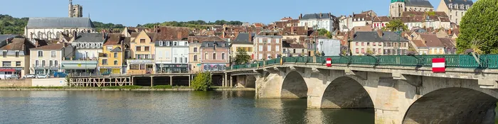 Pont de pierre sur l'Yonne à Joigny, avec les quais, les façades de la vieille ville et un clocher sur la colline