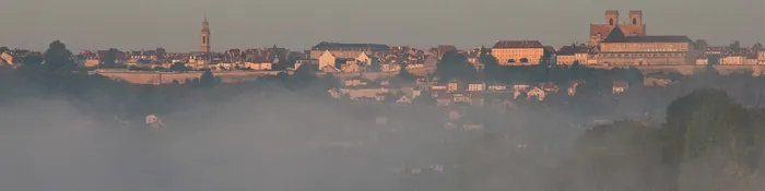 Silhouette de Langres et de la cathédrale Saint-Mammès sur son promontoire, au-dessus de la brume matinale du lac de la Liez