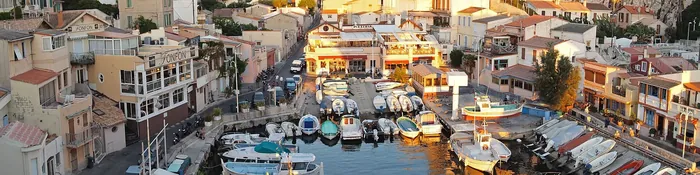 Petit port du Vallon des Auffes à Marseille, barques amarrées entre maisons de pêcheurs et immeubles, au soleil couchant