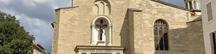 Façade en pierre de l'église Saint-Nicolas de Pertuis, niche au crucifix, devise Liberté Égalité Fraternité et fenêtre gothique