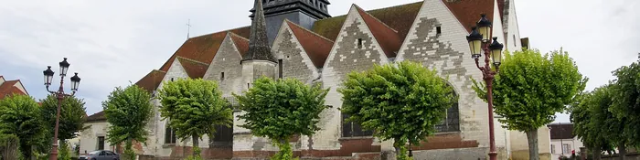 Église Saint-André à pignons de pierre et damier, avec sa flèche d'ardoise, vue depuis la place plantée de Saint-André-les-Vergers