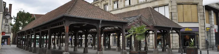 Halles couvertes à charpente de bois sur une place piétonne du centre-ville de Saint-Dizier, devant des immeubles en pierre