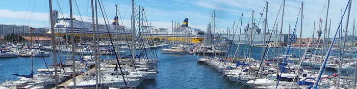 Voiliers amarrés dans le port de plaisance de Toulon, avec les ferries pour la Corse à quai au fond de la rade