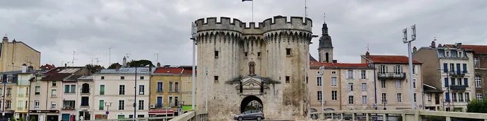 Porte Chaussée de Verdun, ses deux tours crénelées et les façades colorées du quai vues depuis le pont sur la Meuse